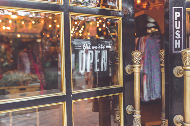 The front door of an establishment with the sign indicating that they are open