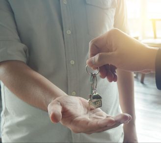 A cropped image of a landlord’s hands giving keys to the tenant