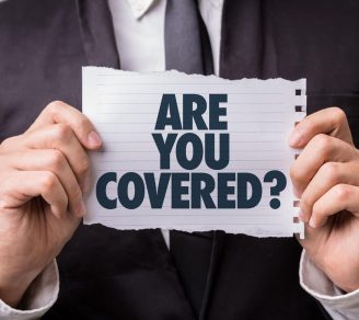 A man holding up a sign that says “Are You Covered?” suggesting the need for businesses to have CGL insurance