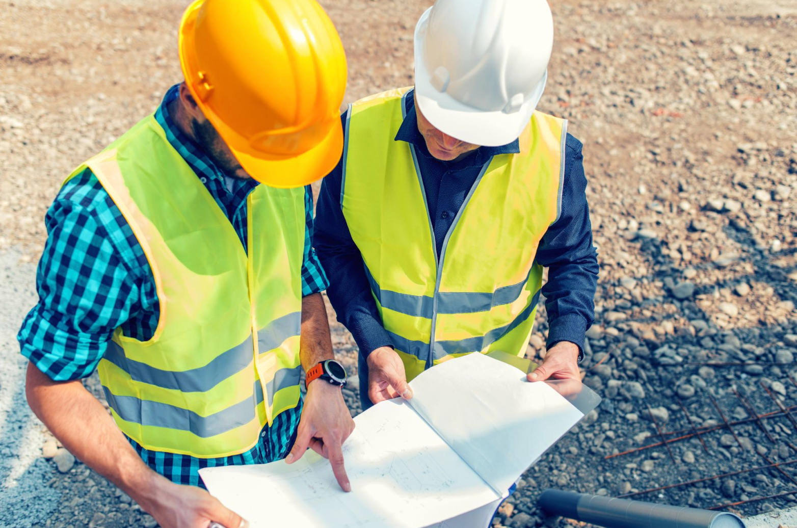 Two contractors reviewing blueprints at a construction site