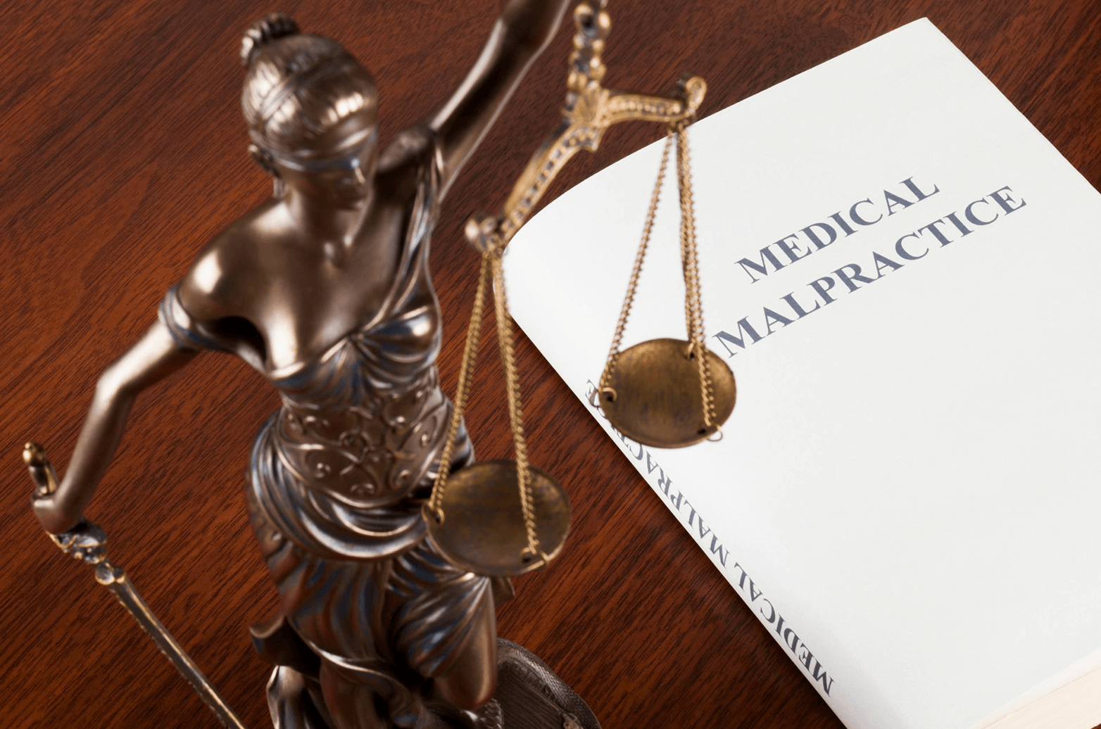 A book about medical malpractice beside a statue of lady justice.