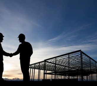 Silhouettes of two contractors shaking hands at a construction site