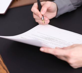 A person reviewing a printed contract with a pen in their hand