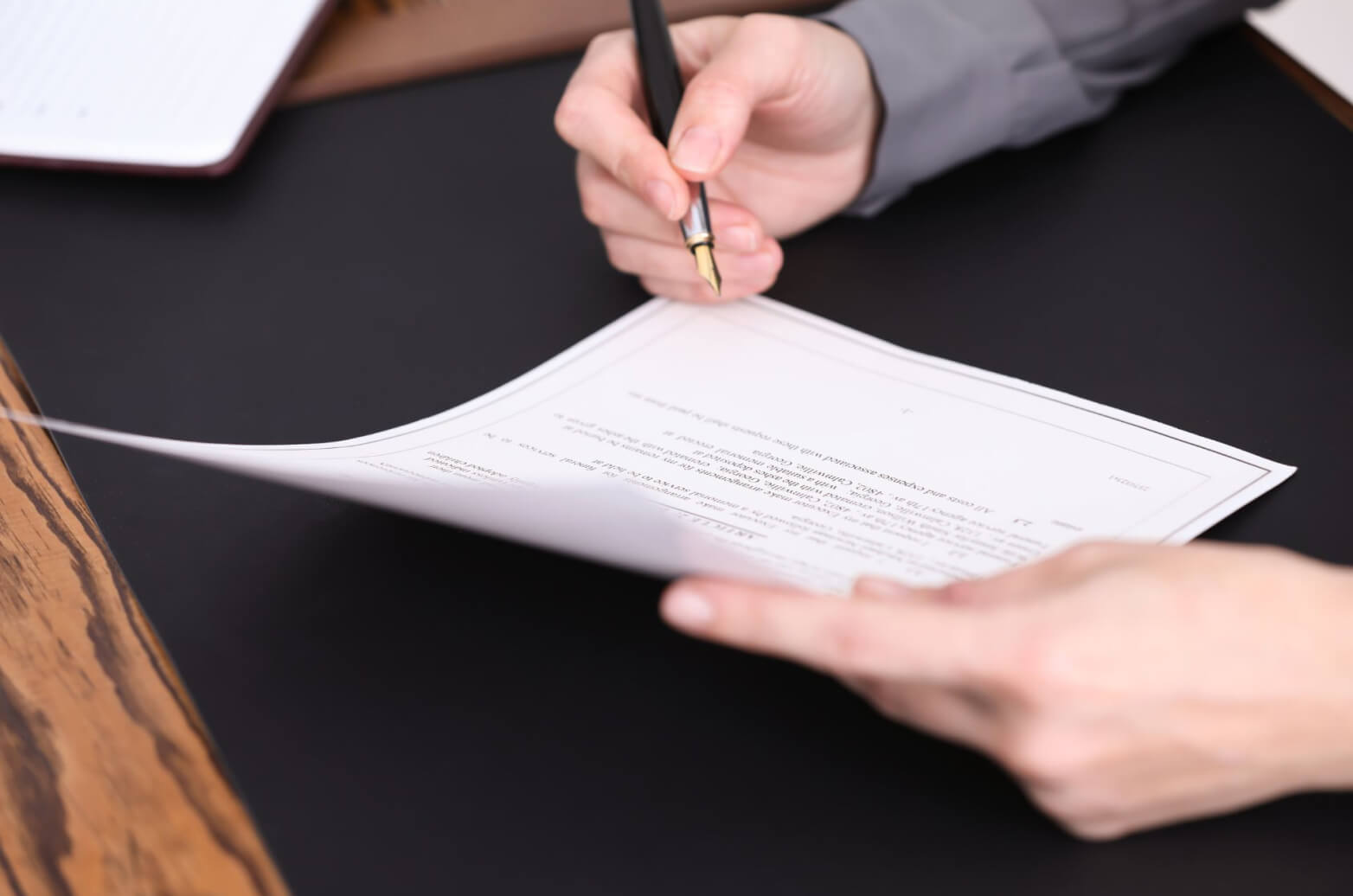 A person reviewing a printed contract with a pen in their hand