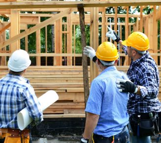 Construction workers working the wooden frame of a house