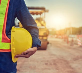 A contractor holds a hard hat by his side on a construction site