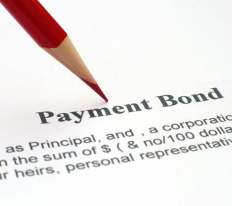 A printed payment bond contract with a red pencil