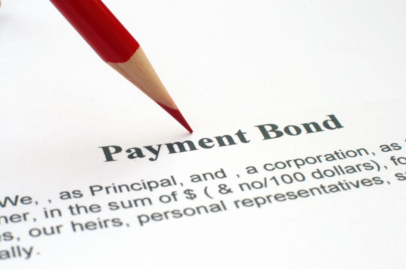 A printed payment bond contract with a red pencil
