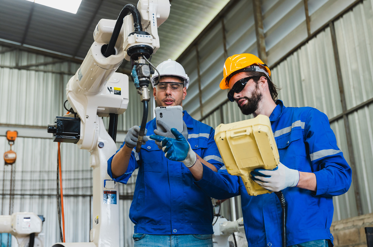 Two people operating a robot welding machine