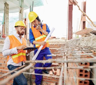 Contractors wearing constructions vests and hard hats looking at construction plans on a job site