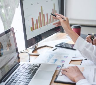 A desk with a laptop and monitor showing data for business risk management strategies