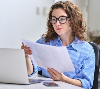 Young businesswoman sitting at desk reviewing papers to determine if she should get Trade Credit Insurance