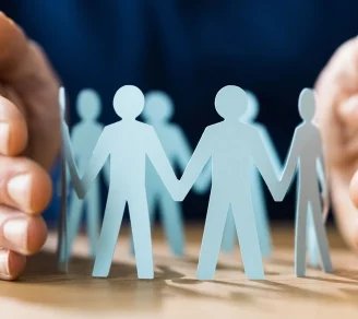 A pair of hands protecting a cutout of people joining hands forming a circle
