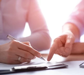 Two individuals, with one holding a pen, reviewing a contract.
