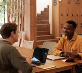 A smiling man being interviewed by HR in a modern office space.