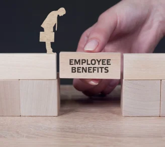 An “Employee benefits” block held by a hand bridges two groups of blocks while an employee cutout stands on one side