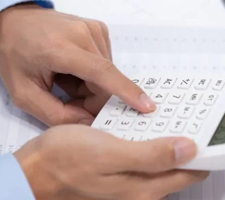 An auditor computing trade credit insurance cost with a calculator